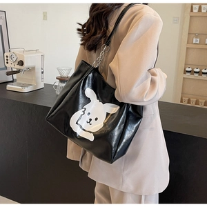 Detail of glossy black tote bag featuring a cute white rabbit print and metal chain strap