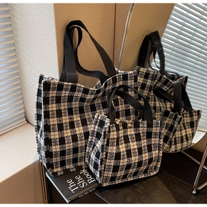 Detail view of large and small black and white plaid tweed tote bags with woven handles