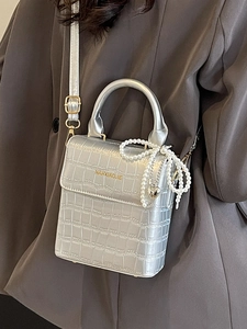 Silver crocodile texture box bag with pearl bow and heart charm on gray suit