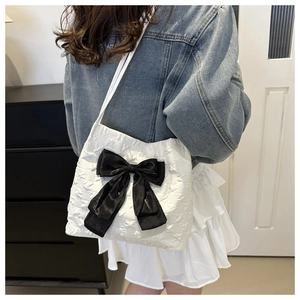 Detail of white tote bag with star embossing and a large black silk bow decoration