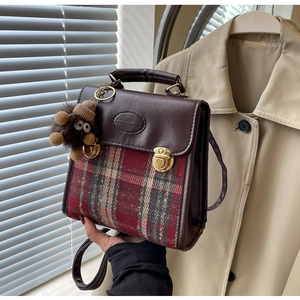 Detail of vintage brown plaid bag with gold buckle and plush monster pendant charm
