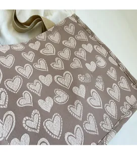 Close-up of heart pattern canvas tote bag with soft texture and khaki handles