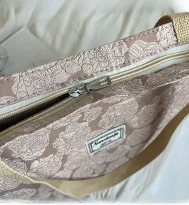 Detail of silver metal zipper and embossed rose jacquard fabric on the pink canvas bag