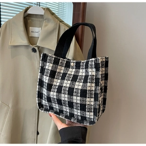 Close-up of black and white checkered tweed tote bag with button closure and black strap