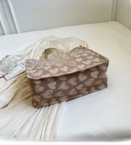 Close-up of brown canvas tote bag featuring cream heart patterns and soft fabric texture