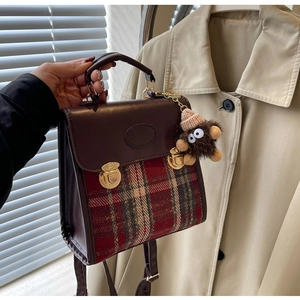 Detail of vintage red and green plaid handbag with leather flap and plush monster charm