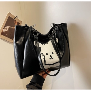 Detail of a large black leather tote bag with white cartoon animal print and metal rings