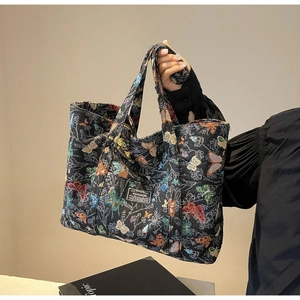 Close-up of black canvas tote bag with colorful butterfly embroidery and fashion label