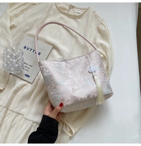 Dettaglio della borsa a secchiello in jacquard rosa con motivo cinese e nappa bianca