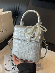 Silver crocodile texture handbag with pearl chain strap and heart charm in a lifestyle set