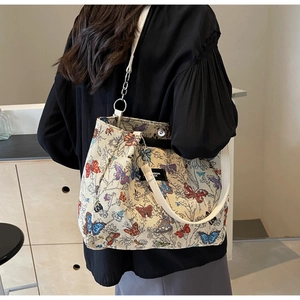 Close-up of butterfly embroidery tote with white leather strap and metal chain detail