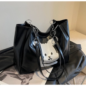 Detail of black tote bag featuring white cartoon animal print and silver metal chain strap