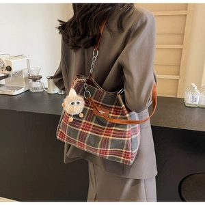 Model wearing vintage plaid tote bag with brown leather straps and plush charm