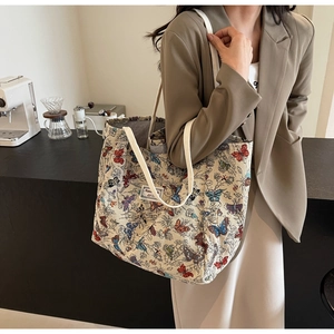 Close-up of large canvas tote bag with colorful butterfly prints on white shoulder strap
