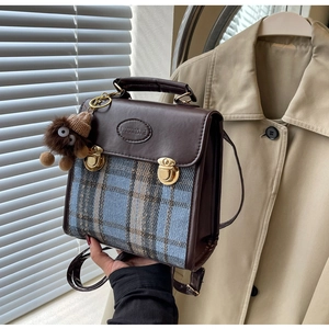 Close-up of retro plaid and brown leather backpack with metal buckles and plush charm