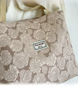 Detail of 3D rose jacquard fabric and vintage woven label on beige canvas tote bag