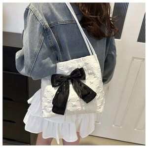 Close-up of white bubble fabric shoulder bag with large black satin bow and straps