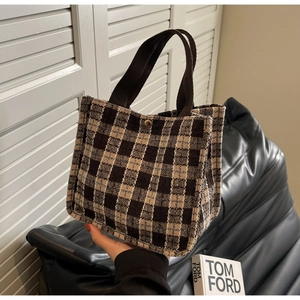 Detail of checkered tote bag showing woven handles and secure gold metal clasp closure