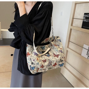 Detail view of canvas tote bag with colorful butterfly embroidery and metal chain strap