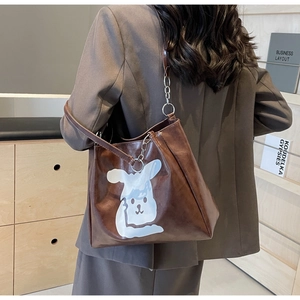Detail of a brown tote bag featuring a white rabbit print and chain shoulder strap