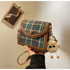 Detail of plaid crossbody bag with brown leather trim and a cute plush toy pendant