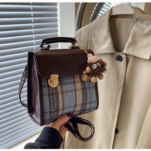 Detail of vintage patchwork crossbody bag featuring brown leather and blue plaid fabric