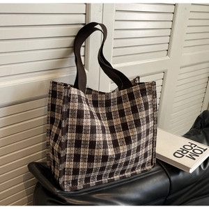Detailed view of the thick woven texture and brown webbing handles on a checkered tote bag