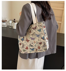 Detail of colorful butterfly jacquard tote bag featuring white canvas shoulder straps