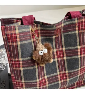 Brown faux fur monster keychain with white eyes and knit hat on a tote bag detail
