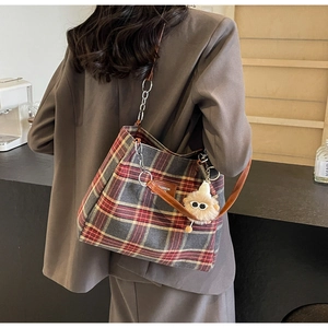 Detail of vintage plaid tote bag with brown leather strap and owl plush pendant