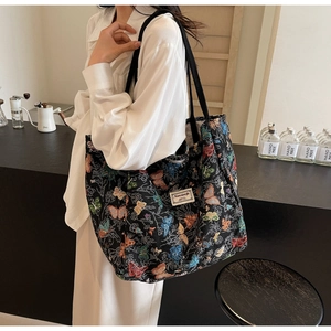 Detail of a black canvas tote bag with butterfly patterns shown in a lifestyle setting