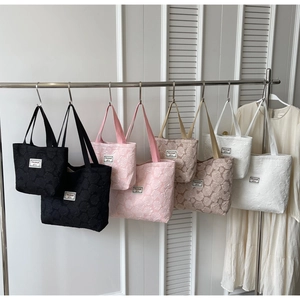 Detail of floral jacquard tote bags in four colors hanging on a display rack