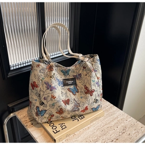 Close-up of beige tote bag featuring colorful butterfly jacquard and Fashion Bags logo