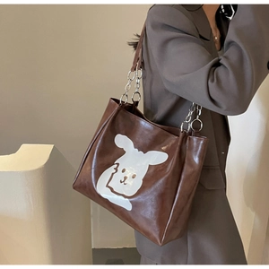 Detail of cartoon rabbit print and metallic chain strap on brown tote bag