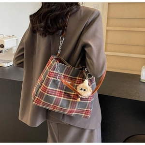 Detail view of retro plaid tote bag with plush charm and chain strap for daily wear