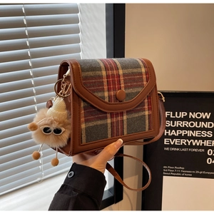 Close-up of retro plaid crossbody bag with a cute brown plush doll pendant