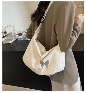 Détail du sac hobo blanc cassé montrant le tissu plissé et la boucle papillon en argent
