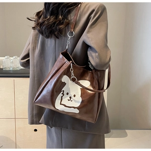Brown faux leather tote bag with white cartoon rabbit print worn by a model