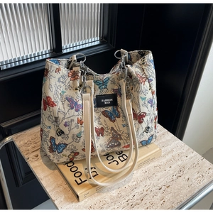 Detailed close-up of ivory canvas tote bag with embroidered butterflies and metal chain