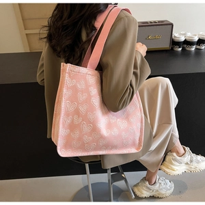Dettaglio della borsa tote in tela rosa con motivi a cuore jacquard e ampi manici intrecciati