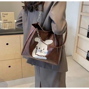 Detail of a brown tote bag featuring a white cartoon rabbit and chain shoulder strap
