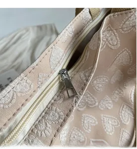 Close-up of silver metal zipper on cream white canvas tote bag with heart jacquard pattern
