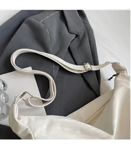 Gros plan du sac beige avec bandoulière réglable et boucle en métal dorée