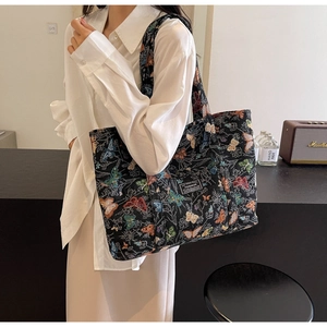 Close-up of black canvas tote bag with colorful butterfly prints and fashion patch detail