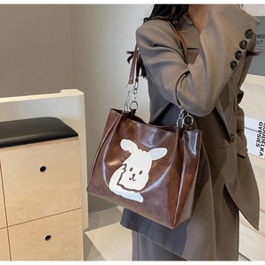 Detail of dark brown leather tote featuring white cartoon rabbit print and chain strap