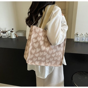 Dettaglio della borsa tote in tela con cuori e ampi manici intrecciati in un caffè
