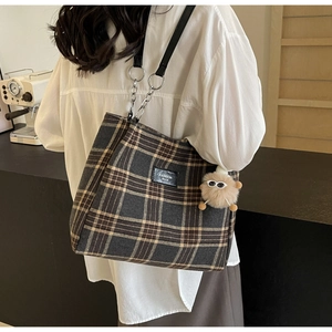 Detail of checkered tote bag with leather chain strap and brown plush eyewear charm