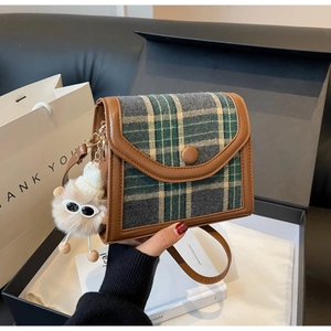 Close-up of a vintage plaid square bag with a creative plush charm and gift packaging