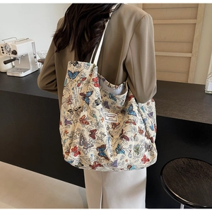 Detail of large canvas tote bag featuring vibrant butterfly prints and reinforced shoulder straps