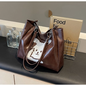 Detail of brown PU leather tote bag with cute cartoon rabbit print and chain handles